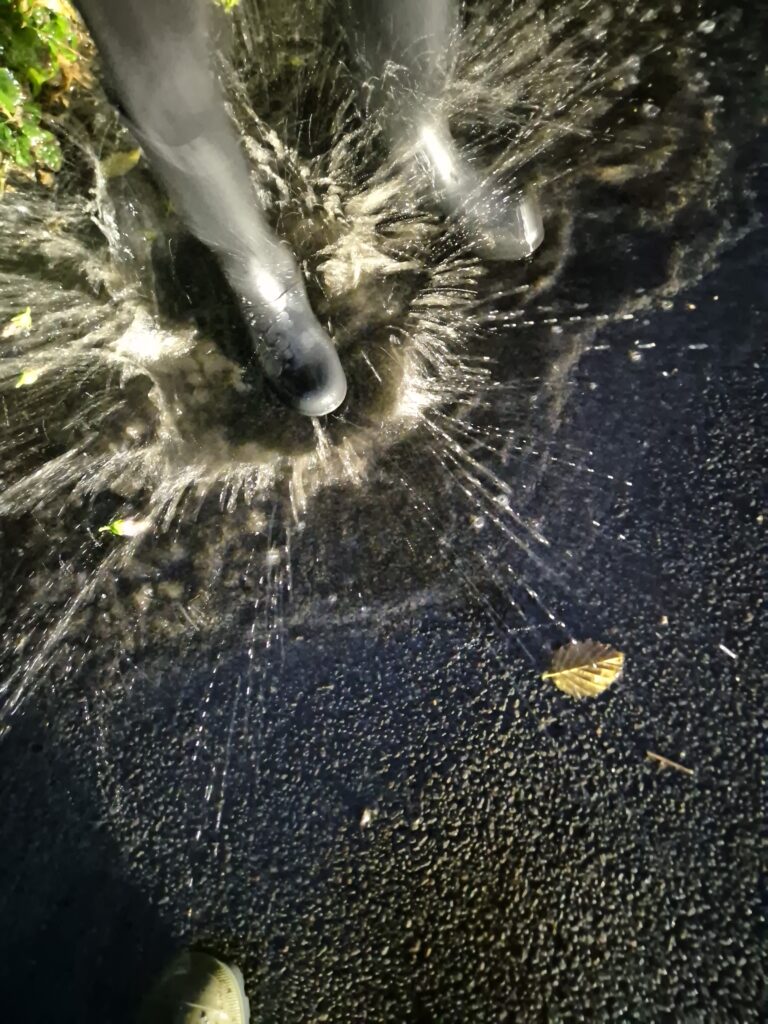 Black boots splashing in a puddle.