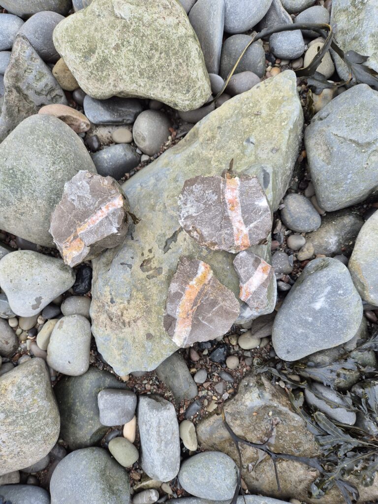 A rock with another colour inside it on the beach