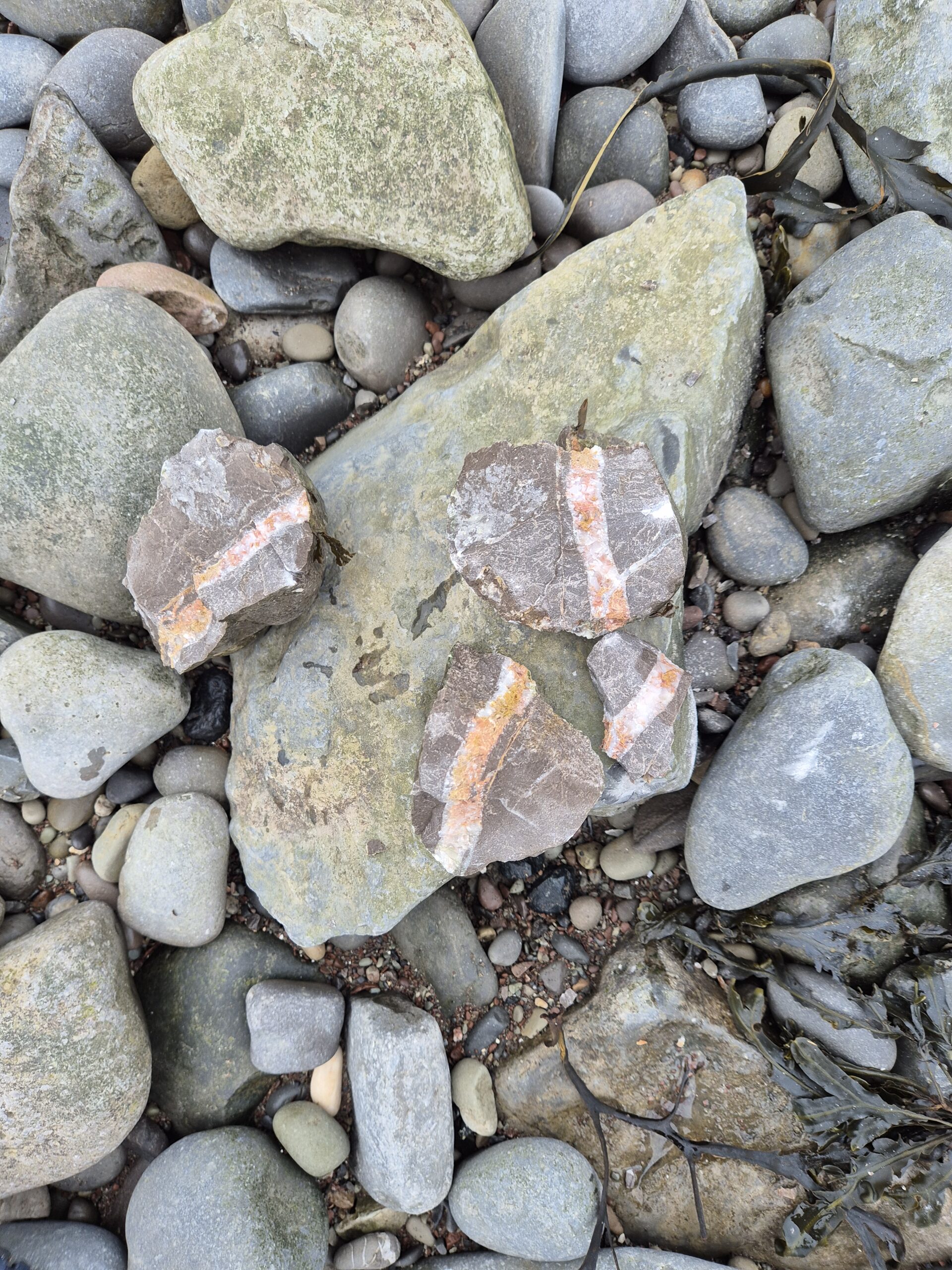 A rock with another colour inside it on the beach